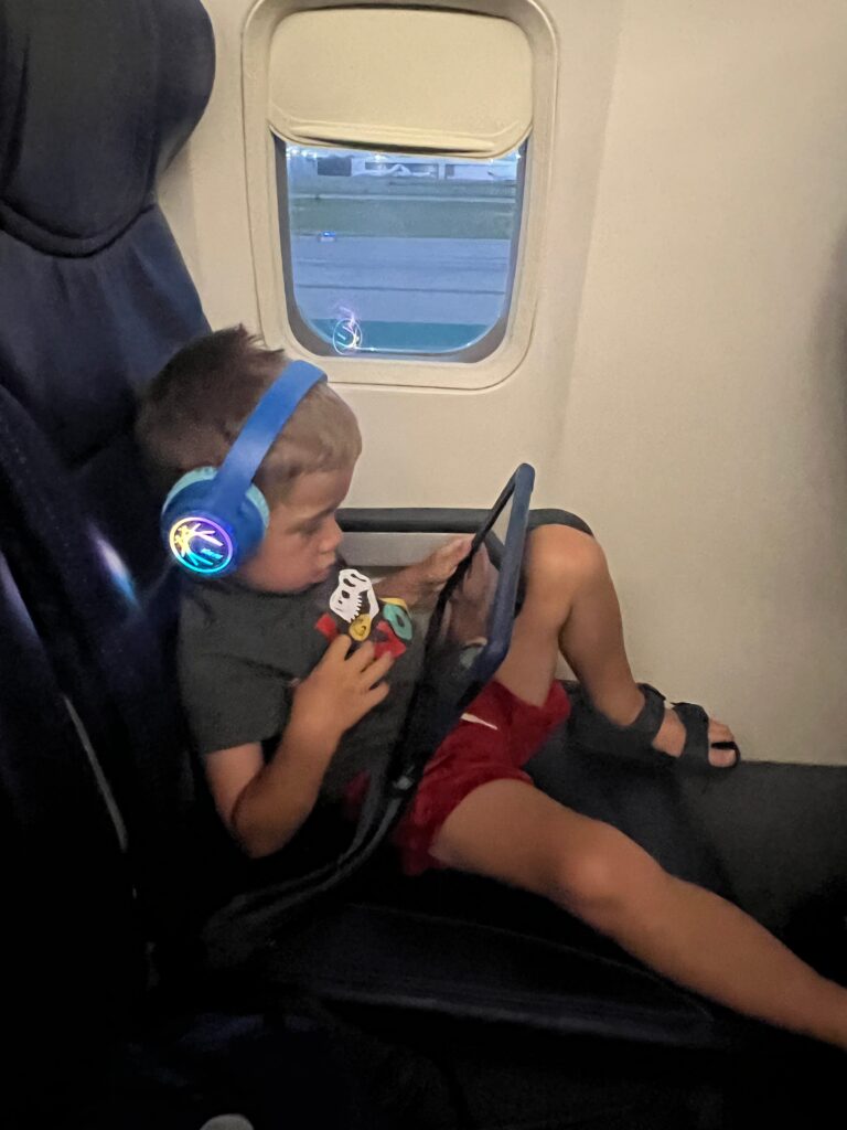 Small child watching an iPad while wearing headphones.